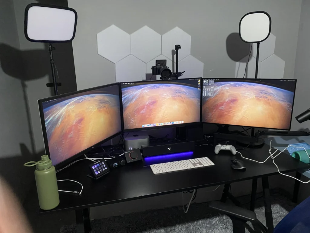 A picture of Ozject's streaming setup--three monitors, some lights, a camera, and some assorted tools on the desk.