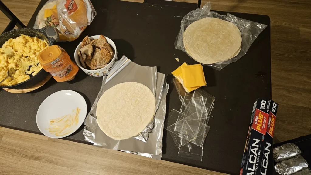 A table filled with the ingredients for meal prepped sausage egg and cheese wraps.
