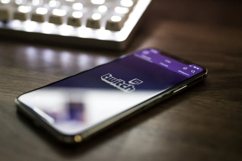 A cellphone on someone's desk, showing the Twitch logo within the Twitch app